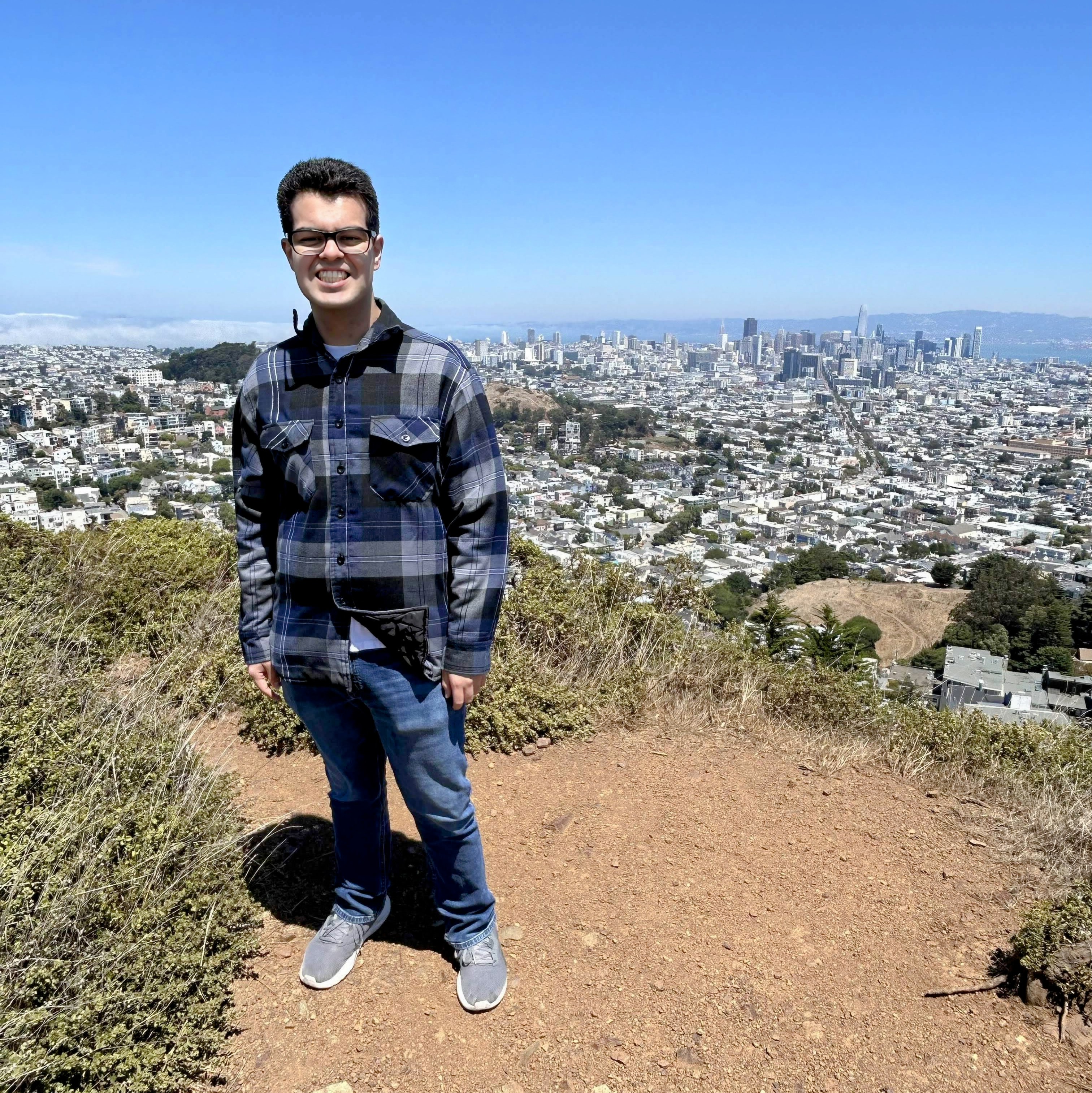 Matthew standing atop a hill with the San Francisco skyline in the background